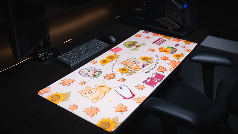 Cozy Desk deskmat in a desktop gaming setup featuring autumn leaves, sunflowers, a cute Pomeranian, anime artwork, and cozy fall-themed illustrations.