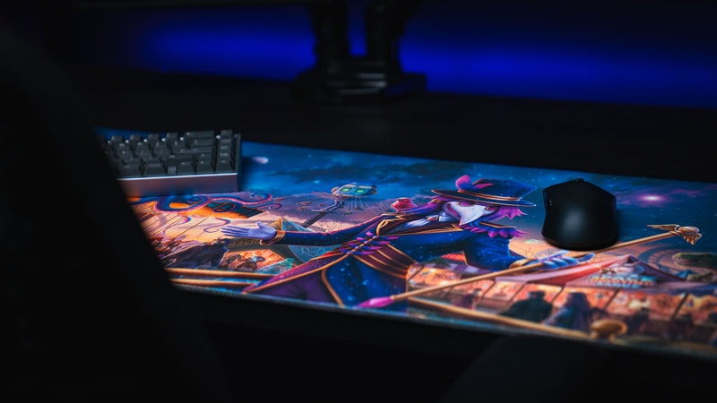 Angled view of the Festival of Feathers gaming deskmat in a blue-lit desktop setup