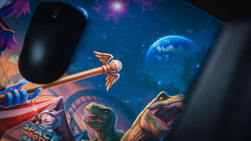 Mouse beside planets and dinosaur artwork on the Crowmedia Festival of Feathers deskmat
