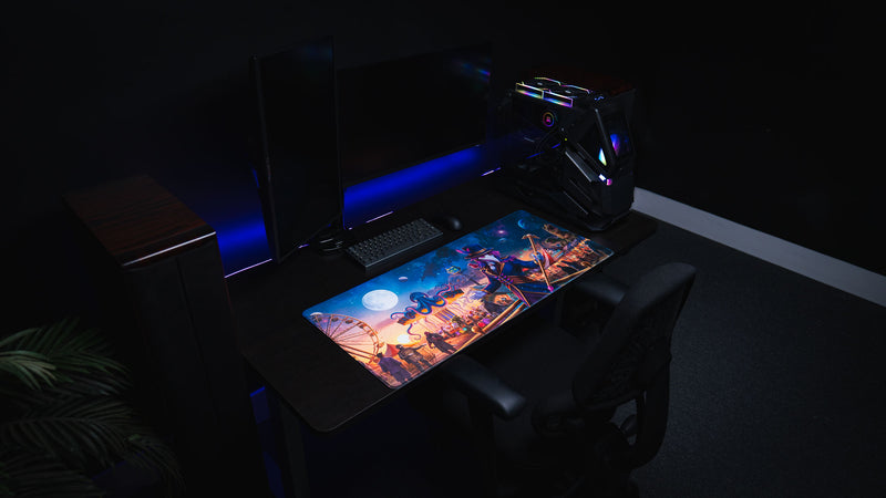 Side view of a dark blue RGB desk setup with the Crowmedia Festival of Feathers gaming deskmat