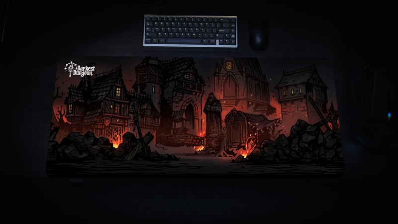 Top-down view of the Darkest Dungeon Design 2 desk mat beneath a keyboard and mouse on a black desk