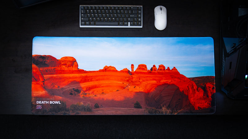 Death Bowl deskmat displayed on a gaming desk, showcasing the sweeping red sandstone basin and dramatic desert landscape of Utah in vivid detail.