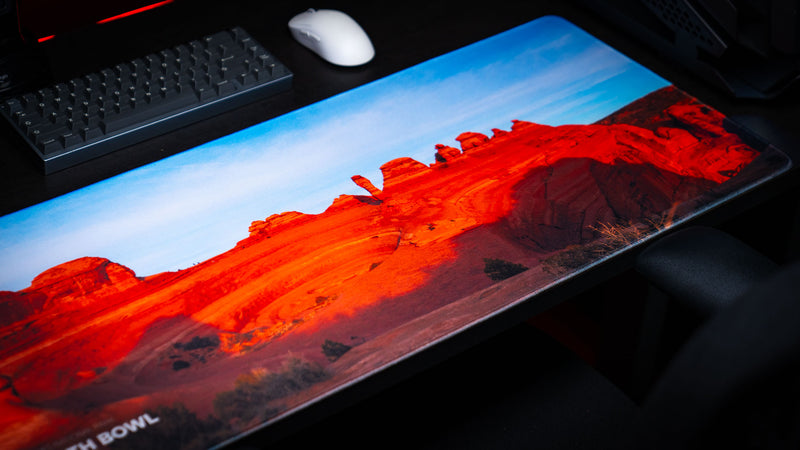 Death Bowl deskmat showcasing the dramatic red sandstone landscape of Arches National Park from an angled perspective, featuring rich desert colors and premium stitched edges.