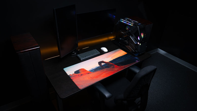 Delicate Arch premium deskmat displayed in a modern gaming setup, featuring iconic Arches National Park photography, stitched edges, and an extended gaming surface.