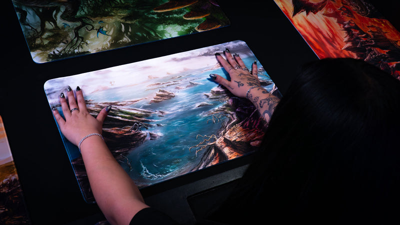 Desolate Island playmat featuring rocky sea cliffs, scattered islands, crashing waves, and a misty fantasy coastline from the Fallen Lands collection.