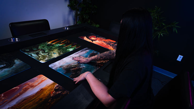 Desolate Island fantasy playmat displayed alongside other Fallen Lands designs, featuring rocky sea cliffs, scattered islands, and turbulent coastal waters.