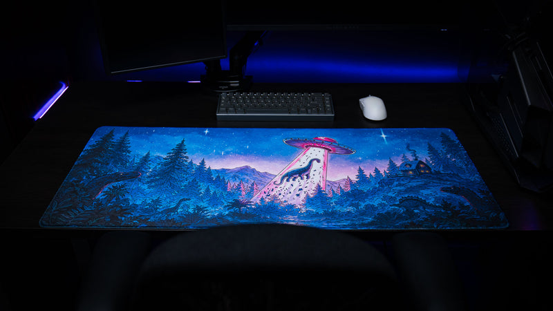 Full view of the Dino Abduction Rust deskmat featuring a UFO abducting a dinosaur in a vibrant prehistoric forest beneath a star-filled night sky.