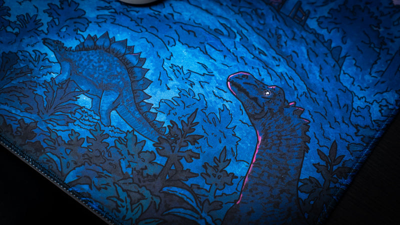 Close-up of the Dino Abduction Rust deskmat showcasing hidden dinosaur illustrations and detailed prehistoric forest artwork near the stitched edge.