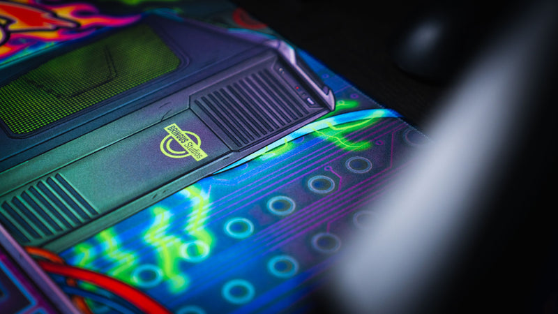 Close-up detail of the E-waste Showdown deskmat by Bringus Studios featuring a retro PC tower, neon circuitry, electric green accents, and vibrant tech-inspired artwork.