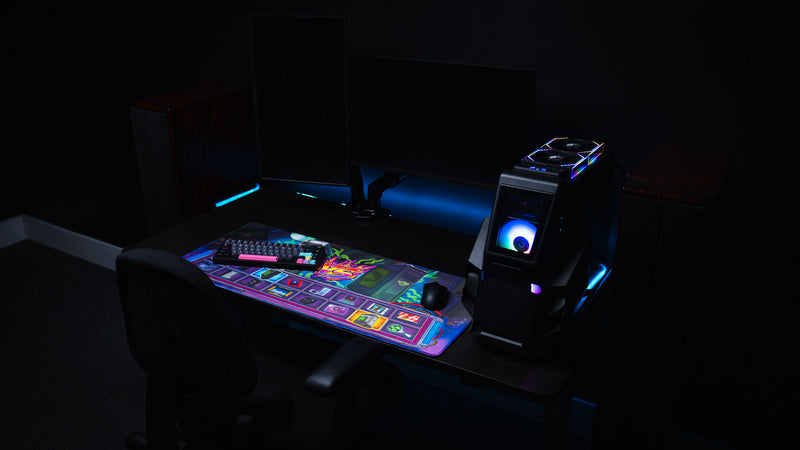 Gaming desk setup featuring the E-waste Showdown deskmat by Bringus Studios with retro tech artwork, colorful electronics icons, mechanical keyboard, RGB gaming PC, and ambient blue lighting.