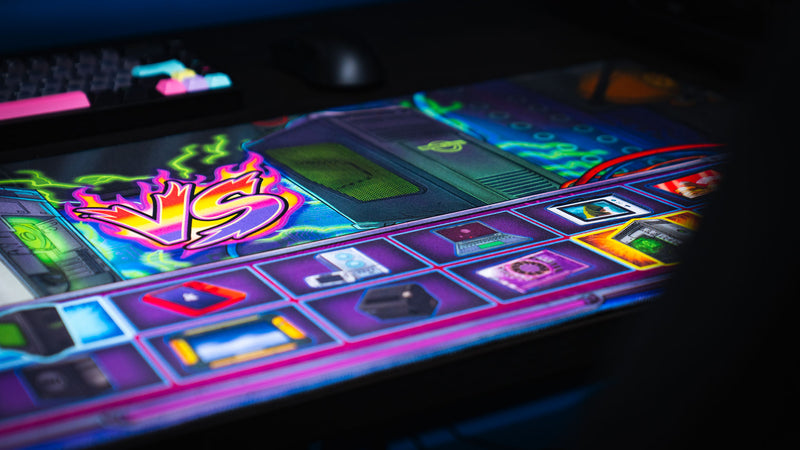 Close-up of the E-waste Showdown deskmat by Bringus Studios featuring a neon VS graphic, retro computer towers, colorful electronics icons, glowing circuitry, and arcade-inspired tech artwork.