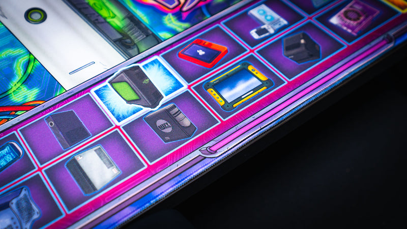Close-up of the E-waste Showdown deskmat by Bringus Studios showcasing collectible retro electronics, gaming hardware, handheld devices, and colorful neon-inspired tech artwork.