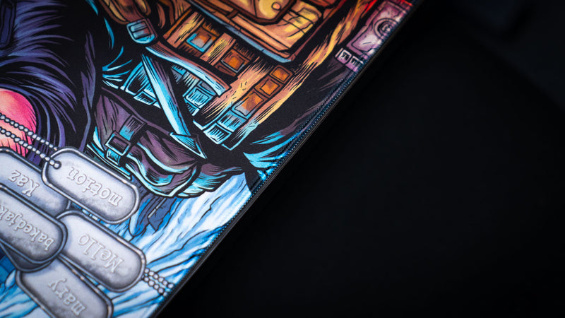 Close-up of the Extraction Boss deskmat by ImOw highlighting the tactical vest, engraved dog tags, premium stitched edge, and vibrant comic-style artwork on a high-quality gaming deskmat.