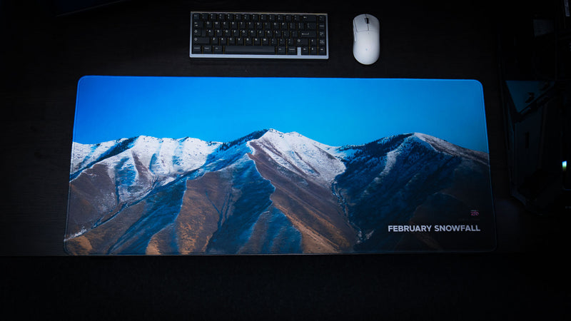 Overhead product photo of the February Snowfall deskmat featuring a panoramic winter mountain landscape from rural Utah.