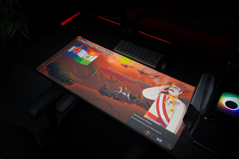 Florius Chaotic Dawn deskmat in a gaming setup beside a keyboard and RGB-lit PC, showing the orange map artwork.