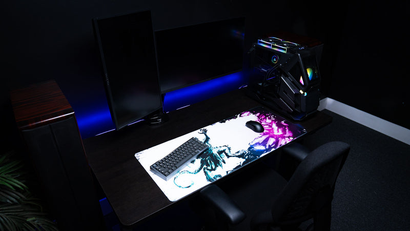 Wide view of the Forbidden Spoils premium XXL gaming deskmat featuring a fantasy rat warrior in a complete RGB gaming setup with keyboard, mouse, dual monitors, and desktop PC.