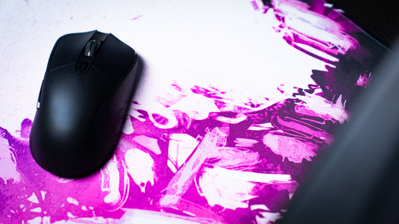 Close-up of a gaming mouse on the Forbidden Spoils premium deskmat, highlighting the smooth tracking surface and vibrant purple fantasy artwork.