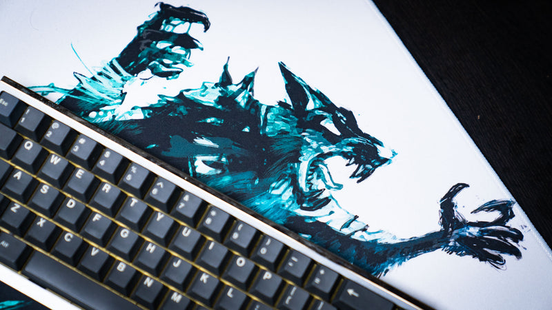 Close-up of the Forbidden Spoils premium gaming deskmat showcasing the snarling fantasy rat warrior artwork with expressive brush strokes beside a mechanical keyboard.