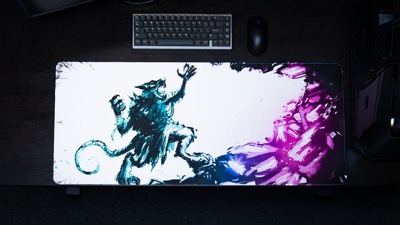 Top-down view of the Forbidden Spoils premium XXL gaming deskmat featuring a fantasy rat warrior with a vibrant purple crystal backdrop in a complete keyboard and mouse gaming setup.