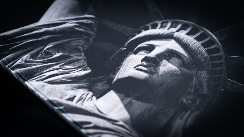 Close-up of the Freedom deskmat featuring detailed monochrome Statue of Liberty artwork, premium stitched edges, smooth cloth surface, and an extended gaming mouse pad design.