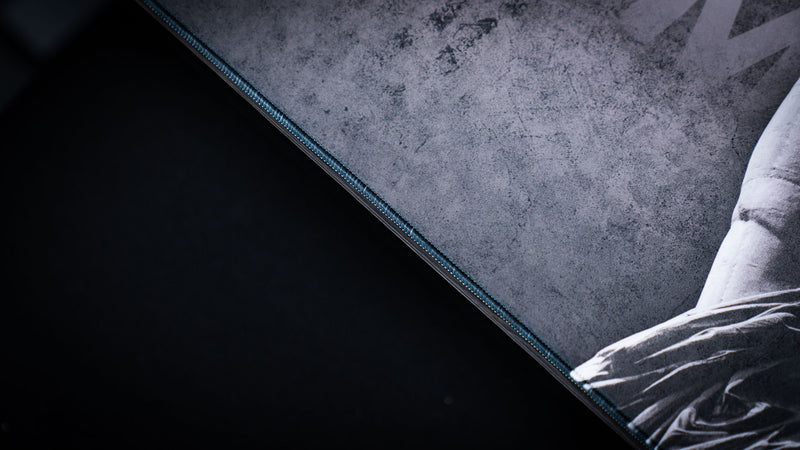 Close-up of the Freedom deskmat highlighting the premium stitched edge, textured grayscale surface, and durable oversized gaming desk mat construction.