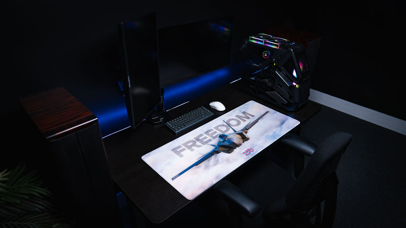 Freedom in the Sky America 250 deskmat displayed in a dark RGB gaming room with fighter jet artwork, keyboard, mouse, and PC setup.