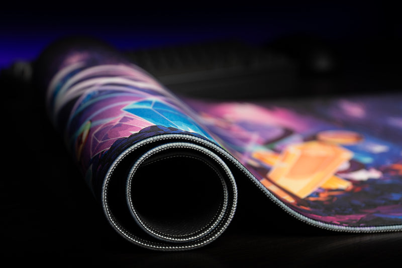GHOSTYMPA's Perplexray's Paradise deskmat with one edge lifted, revealing its black underside beside crystal artwork.