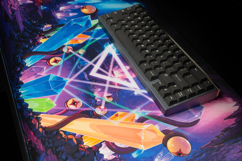 Close-up of the rounded stitched corner on GHOSTYMPA's Perplexray's Paradise deskmat beneath pink crystal artwork.