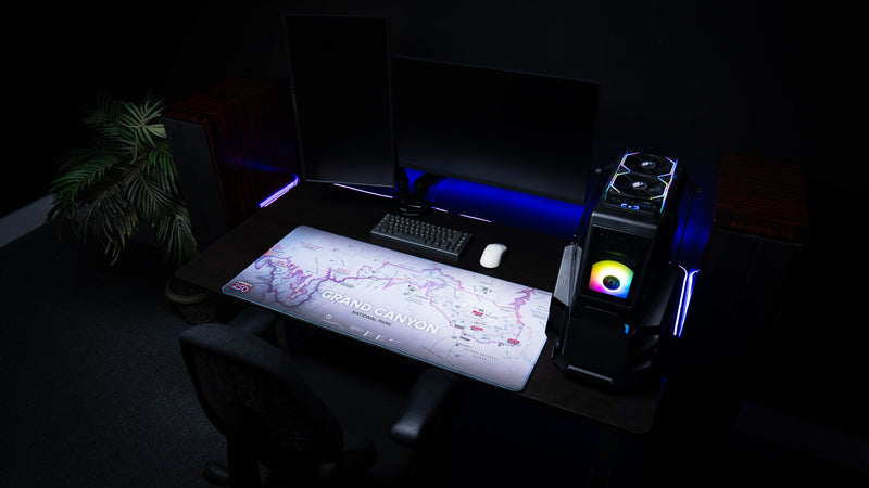 Grand Canyon Purple deskmat featuring a purple topographic map of Grand Canyon National Park displayed on a modern RGB gaming desk with dual monitors, mechanical keyboard, and custom PC.