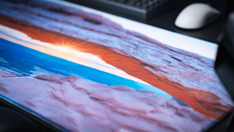 Close-up of the Grand Mesa Sunrise deskmat showcasing Mesa Arch glowing at sunrise in Canyonlands National Park with crisp HD detail, premium stitched edges, and a smooth gaming surface.
