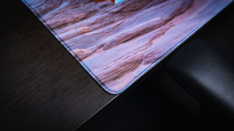 Close-up of the Grand Mesa Sunrise deskmat corner showcasing premium stitched edges, durable craftsmanship, and vibrant Mesa Arch sunrise photography from Canyonlands National Park.