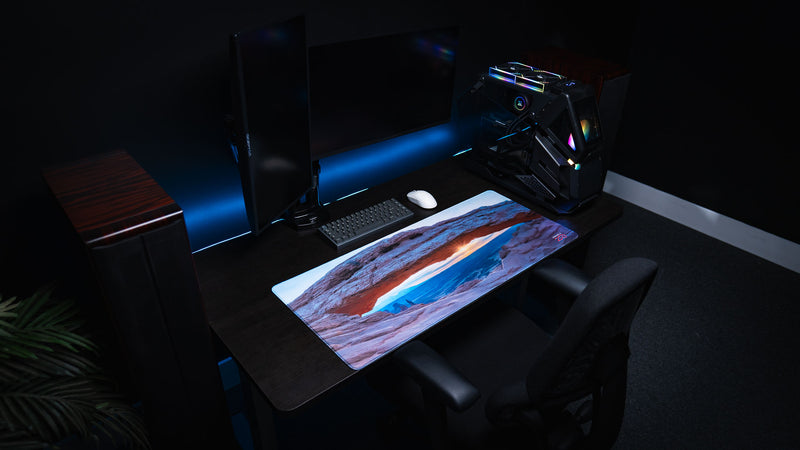 Grand Mesa Sunrise deskmat displayed in a modern gaming setup, featuring Mesa Arch at sunrise in Canyonlands National Park with vibrant HD photography and premium stitched edges.