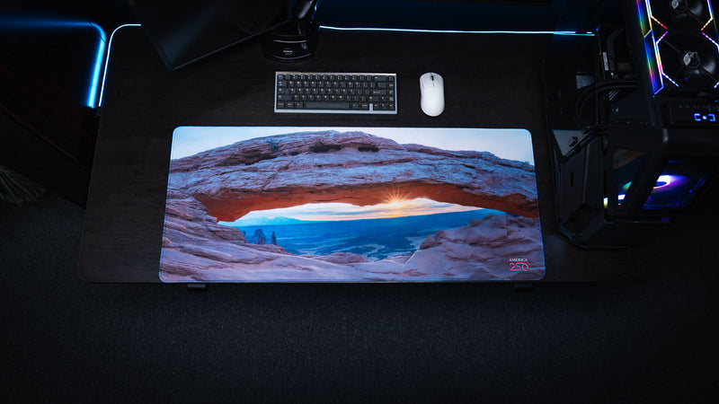 Top-down view of the Grand Mesa Sunrise deskmat featuring Mesa Arch at sunrise in Canyonlands National Park with vibrant HD photography, premium stitched edges, and a spacious gaming surface.