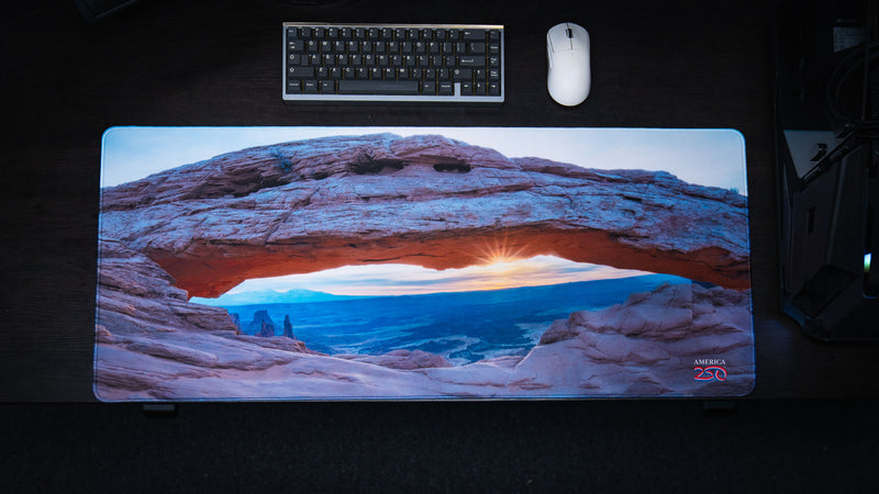 Top-down view of the Grand Mesa Sunrise deskmat showcasing Mesa Arch at sunrise in Canyonlands National Park with vibrant HD photography, premium stitched edges, and a spacious gaming surface.