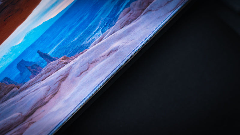 Close-up of the Grand Mesa Sunrise deskmat highlighting the premium stitched edge, smooth gaming surface, and vibrant Mesa Arch sunrise photography from Canyonlands National Park.