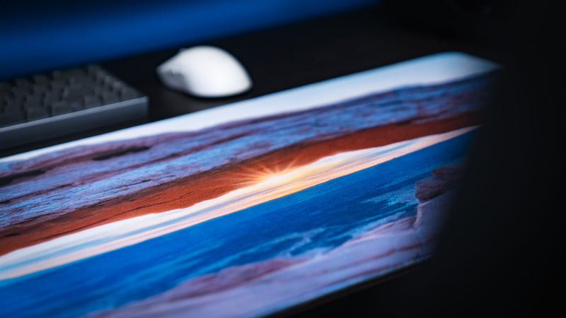 Close-up of the Grand Mesa Sunrise deskmat capturing the sunrise beneath Mesa Arch in Canyonlands National Park with vivid HD detail, premium stitched edges, and a smooth gaming surface.