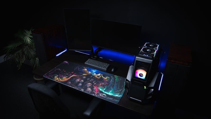 Wide gaming setup with the Grim Kleeper Dominion of the Dark desk mat across a dark workstation