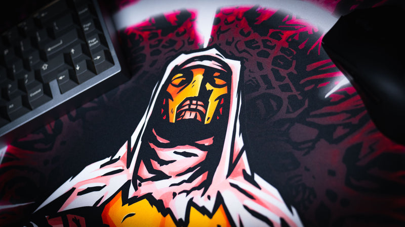 Close detail of the hooded crusader face between a keyboard and mouse on the Spare Them desk mat