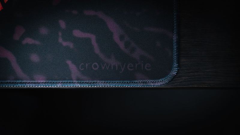 Close detail of the creator signature and stitched border on the Grim Kleeper Spare Them desk mat