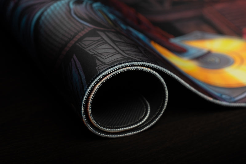 Close-up of the rolled Head Hunters deskmat showing its stitched edge and textured black underside.