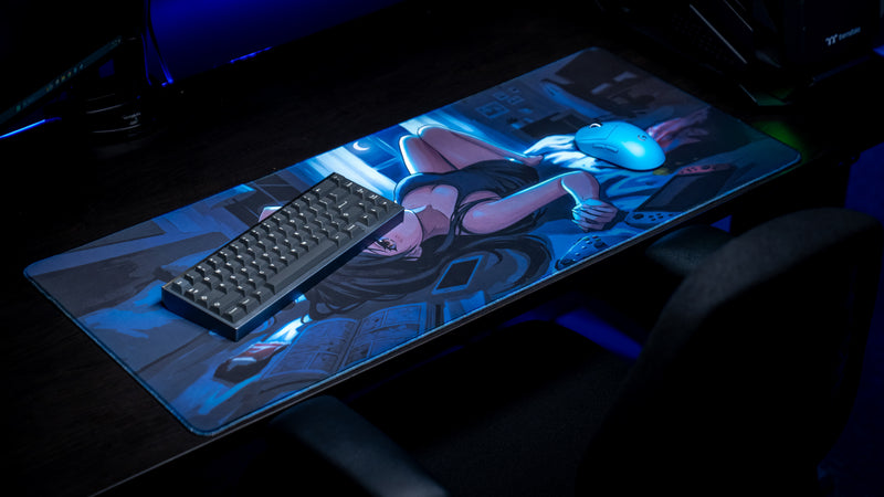 Hello Kiko After Hours deskmat displayed in a gaming setup featuring a moonlit anime bedroom scene with keyboard, mouse, handheld console, manga, and cozy nighttime ambiance.