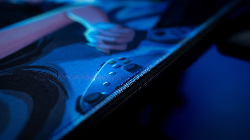 Close-up of the Hello Kiko After Hours deskmat featuring a game controller illustration, premium stitched edge, and vibrant blue nighttime artwork.