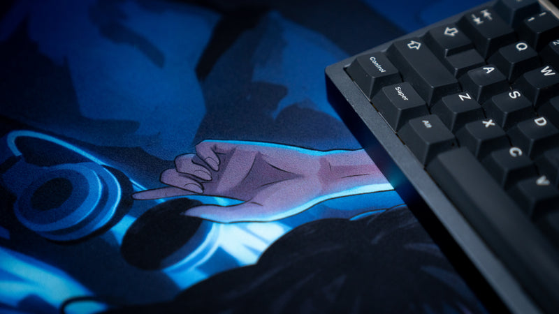 Detailed close-up of the Hello Kiko After Hours deskmat featuring the character's hand beside gaming headphones under a keyboard with soft blue nighttime lighting.
