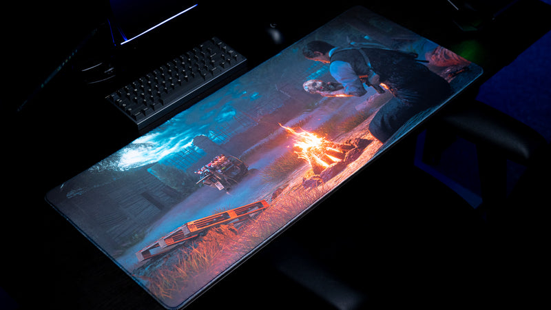 Angled view from the left of Hens The Last Campfire deskmat showing the campfire, generator, and seated character.