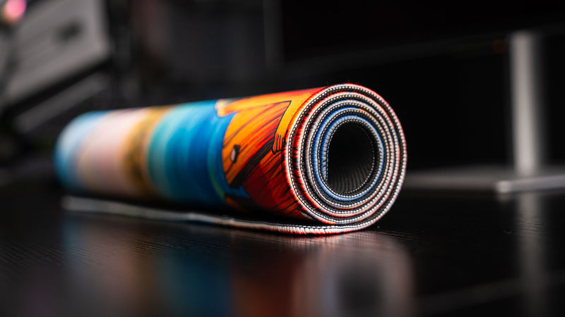 Rolled-up How Do You Fish deskmat by Posty showing premium stitched edges, vibrant dock artwork, and flexible construction ready for storage or travel.