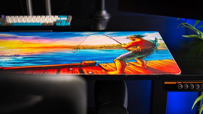 Posty's How Do You Fish deskmat featuring a fisherman casting into the ocean during a colorful sunset.