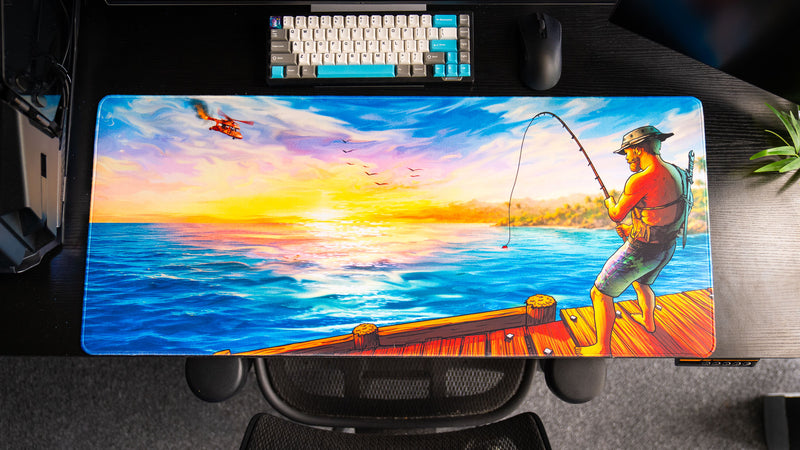 Posty's How Do You Fish deskmat displayed in a gaming setup beneath a mechanical keyboard and mouse, showcasing the full sunset fishing scene.