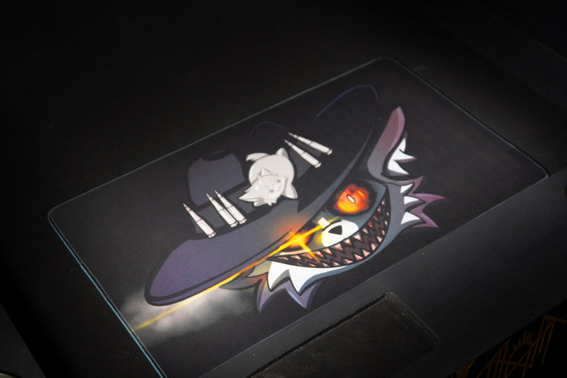 Angled view of Iddqd's Chonk Mat playmat on a dark gaming table, showing the cowboy cat artwork and stitched border.