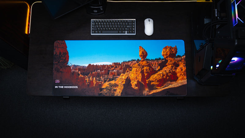 Overhead view of the In the Hoodoos Bryce Canyon National Park deskmat featuring striking hoodoo formations, vivid desert colors, America 250 branding, and a premium gaming desk setup.