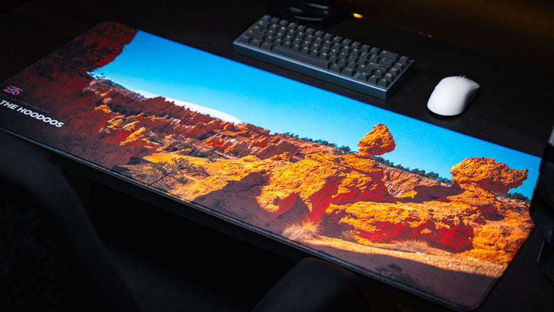 Angled view of the In the Hoodoos Bryce Canyon National Park deskmat showcasing vibrant hoodoo formations, vivid blue skies, premium stitched edges, and a smooth gaming surface.